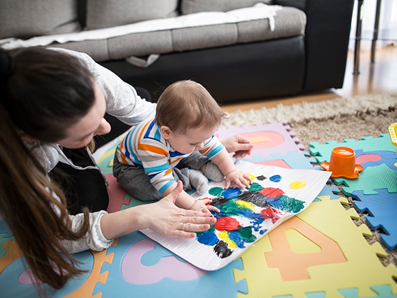 Una mujer y un bebé jugando en una alfombra colorida.