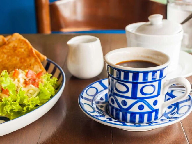 Quesadilla de Espinacas con Guacamole Una taza blanca y azul que contiene café y al lado un plato con ensalada verde y quesadillas